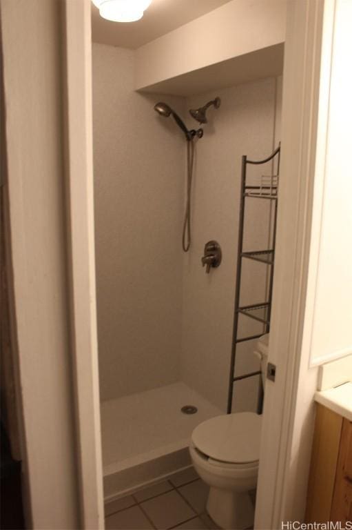 bathroom featuring tile patterned flooring, a shower, vanity, and toilet