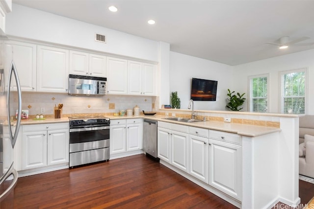 kitchen with appliances with stainless steel finishes, sink, dark hardwood / wood-style flooring, kitchen peninsula, and white cabinetry