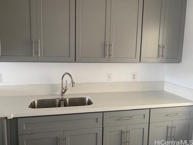 kitchen with gray cabinetry, a sink, and light countertops