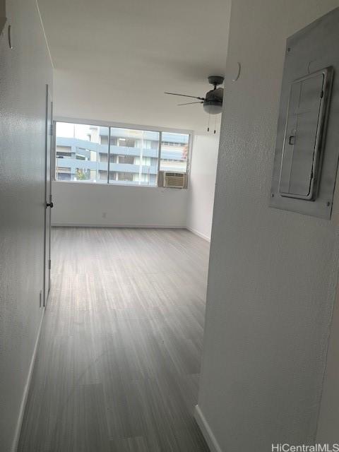 empty room featuring cooling unit, ceiling fan, electric panel, and baseboards