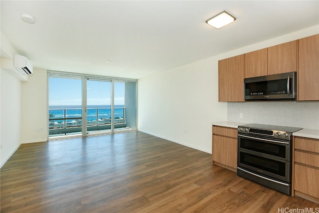 kitchen featuring an AC wall unit, dark wood-type flooring, a wall of windows, appliances with stainless steel finishes, and a water view