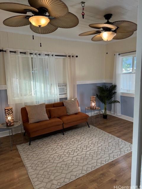 living area featuring ceiling fan, ornamental molding, wood finished floors, and cooling unit