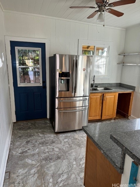 kitchen featuring wood ceiling, ceiling fan, stainless steel fridge with ice dispenser, wood walls, and sink