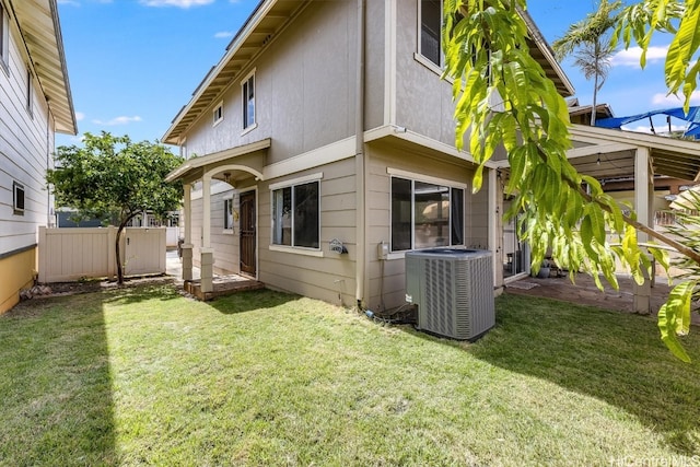 rear view of house with central AC and a lawn