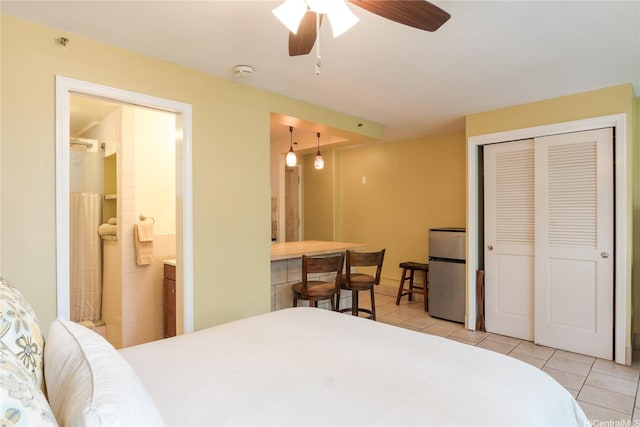 134 Kapahulu Ave Unit 219, Honolulu, HI 96815 - bedroom with freestanding refrigerator, light tile patterned floors, a closet, ensuite bath, and ceiling fan