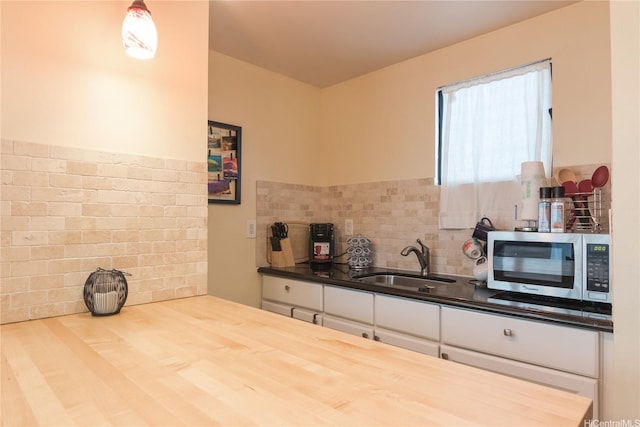 134 Kapahulu Ave Unit 219, Honolulu, HI 96815 - kitchen featuring stainless steel microwave, white cabinetry, backsplash, and butcher block countertops
