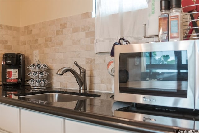 kitchen with decorative backsplash, white cabinetry, and sink