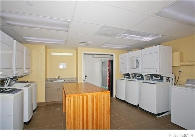 clothes washing area with stacked washer / dryer, sink, separate washer and dryer, and dark tile patterned flooring