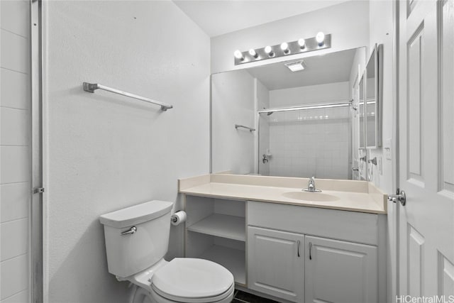 bathroom with toilet, vanity, and tiled shower