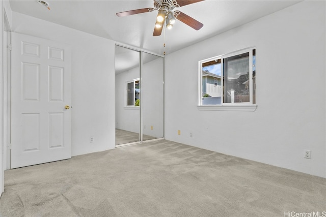 unfurnished bedroom featuring light carpet, a closet, and ceiling fan