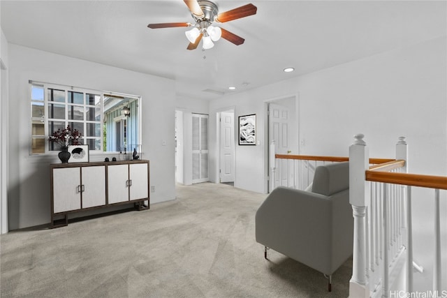 living area featuring light colored carpet and ceiling fan