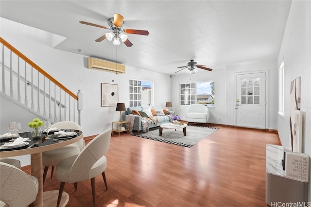 living room featuring ceiling fan, an AC wall unit, wood-type flooring, and a textured ceiling