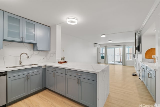 kitchen with kitchen peninsula, decorative backsplash, sink, and light hardwood / wood-style flooring