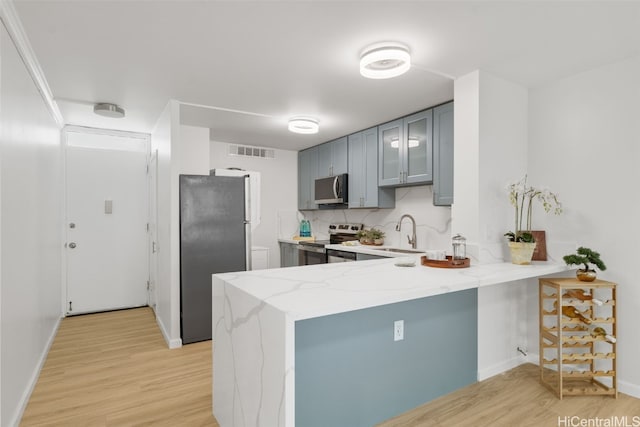 kitchen featuring gray cabinetry, sink, stainless steel appliances, kitchen peninsula, and light hardwood / wood-style floors