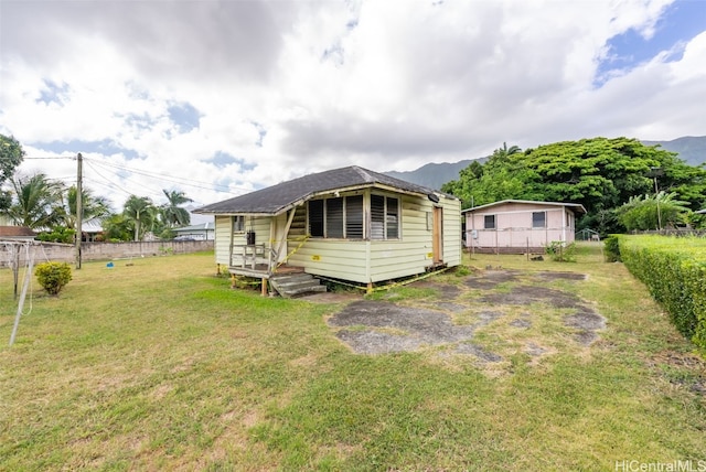 back of property with a mountain view and a lawn