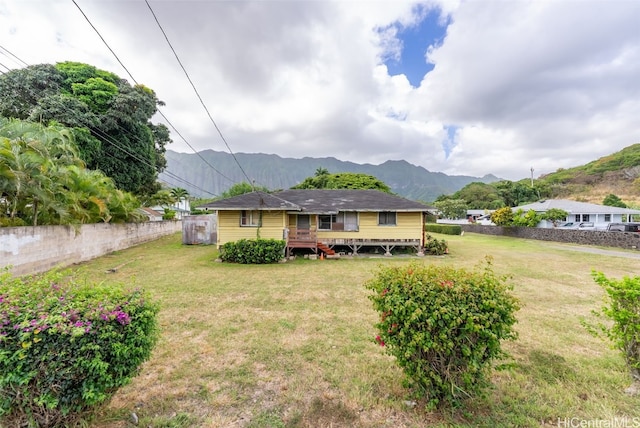 rear view of house featuring a deck with mountain view and a lawn