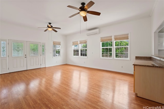 unfurnished living room with light hardwood / wood-style flooring, a wall mounted air conditioner, and ceiling fan