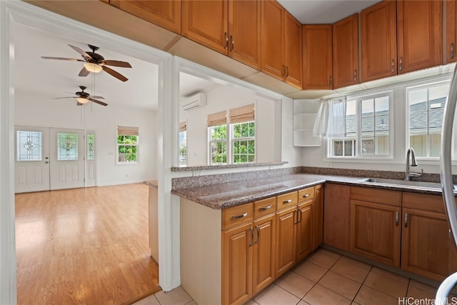 kitchen featuring light hardwood / wood-style flooring, kitchen peninsula, a wall mounted air conditioner, sink, and ceiling fan