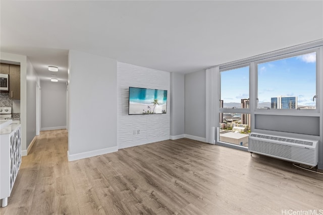 unfurnished living room featuring light hardwood / wood-style floors and a wall mounted air conditioner