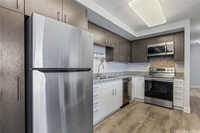 kitchen featuring white cabinets, tasteful backsplash, sink, light hardwood / wood-style floors, and stainless steel appliances