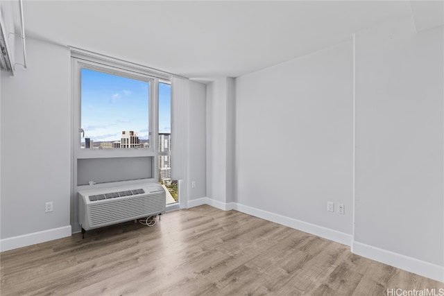 spare room featuring a wall mounted AC and light hardwood / wood-style flooring