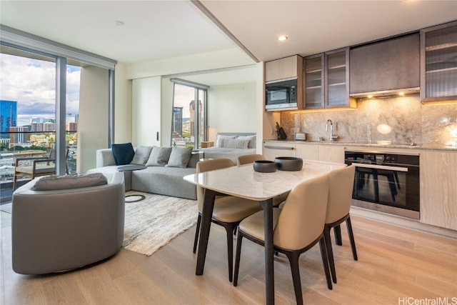 interior space featuring oven, tasteful backsplash, built in microwave, light hardwood / wood-style floors, and sink