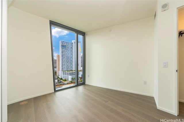 spare room with a wealth of natural light, hardwood / wood-style flooring, and floor to ceiling windows