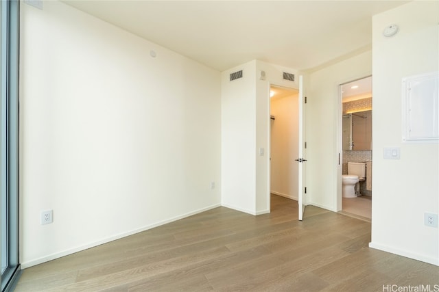 unfurnished bedroom featuring a walk in closet, hardwood / wood-style flooring, and ensuite bath