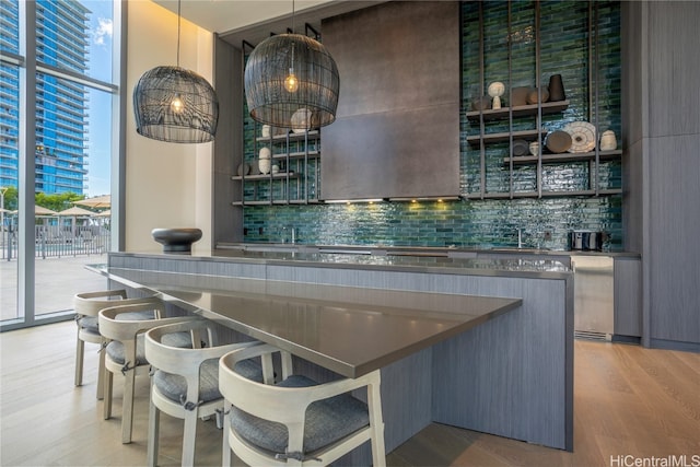 bar featuring light hardwood / wood-style floors, decorative light fixtures, and backsplash