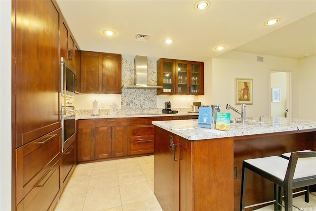 223 Saratoga Rd Unit 2607, Honolulu, HI 96815 - kitchen with wall chimney exhaust hood, a breakfast bar area, oven, glass insert cabinets, and light stone counters