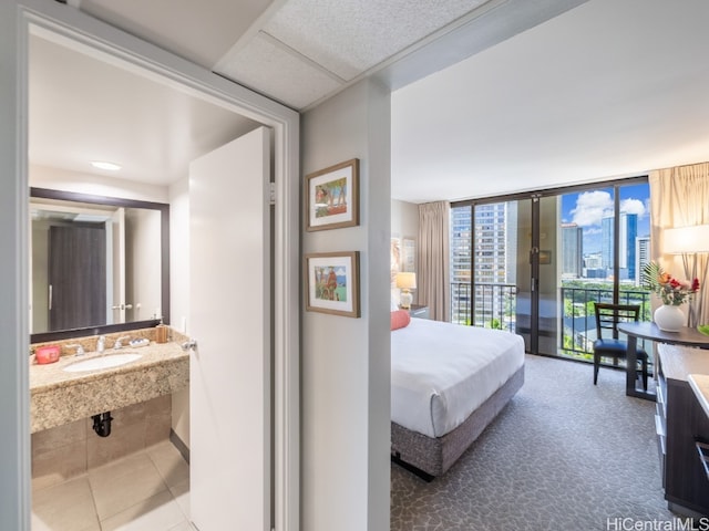 bedroom with access to exterior, sink, tile patterned floors, and floor to ceiling windows