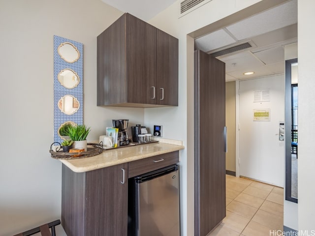 kitchen with stainless steel fridge, dark brown cabinets, and light tile patterned floors