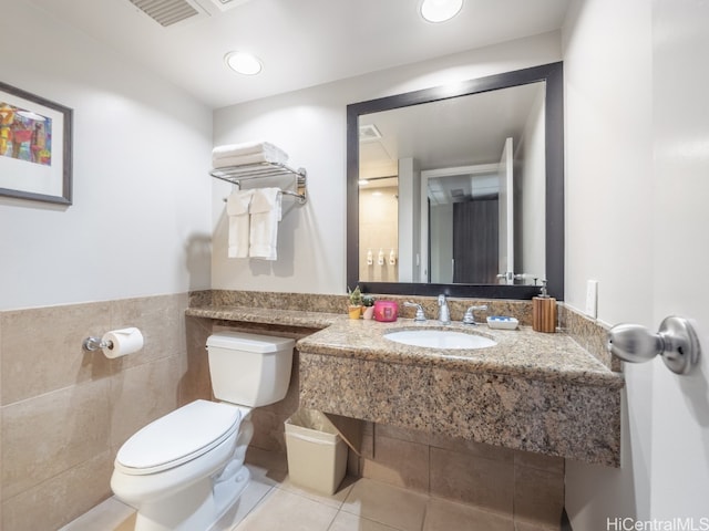 bathroom featuring toilet, sink, tile walls, and tile patterned flooring