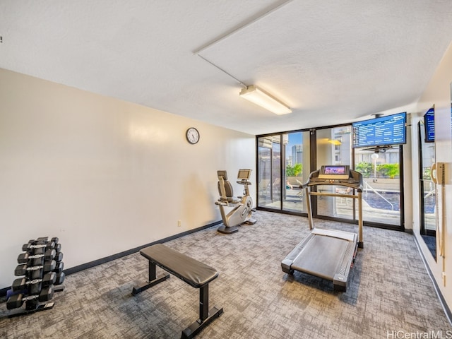 gym featuring a textured ceiling, carpet floors, and a wall of windows