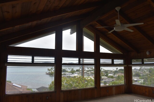 unfurnished sunroom with vaulted ceiling with beams, a water view, ceiling fan, and a healthy amount of sunlight