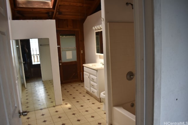 bathroom with vanity, wooden walls, vaulted ceiling with skylight, toilet, and wood ceiling