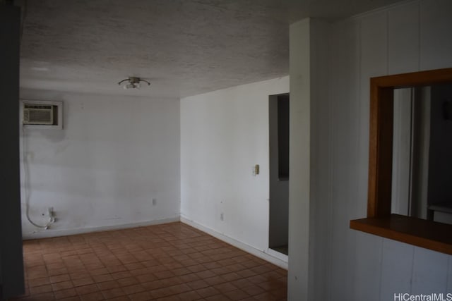 tiled empty room with a textured ceiling and a wall unit AC