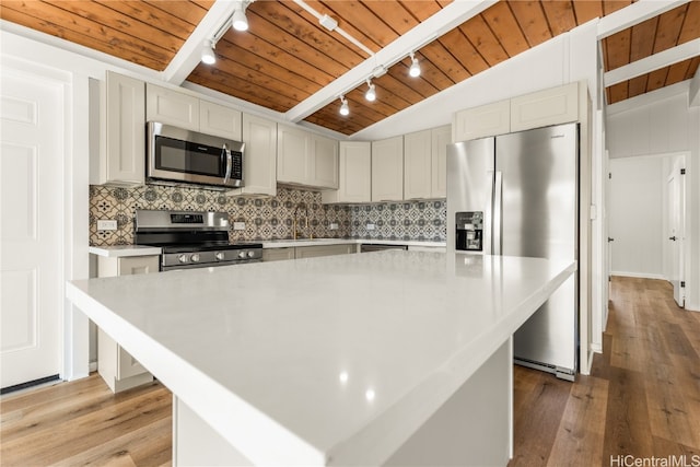 kitchen featuring lofted ceiling with beams, a center island, appliances with stainless steel finishes, wood ceiling, and light hardwood / wood-style flooring