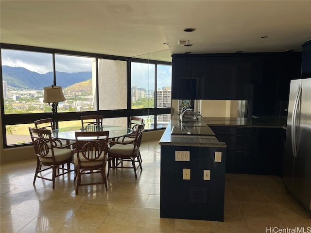 interior space with kitchen peninsula, light tile patterned floors, stainless steel refrigerator, black electric cooktop, and a mountain view