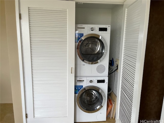 laundry area with stacked washer and clothes dryer and tile patterned flooring