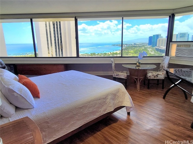 bedroom with cooling unit, multiple windows, wood-type flooring, and a water view