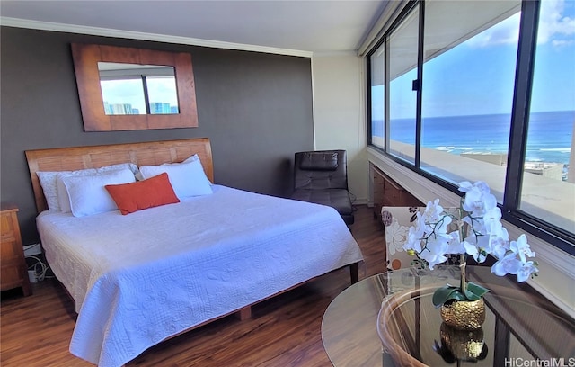 bedroom with crown molding, dark hardwood / wood-style floors, and a water view