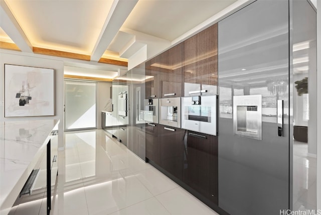 kitchen featuring light tile patterned floors, light stone counters, and beam ceiling