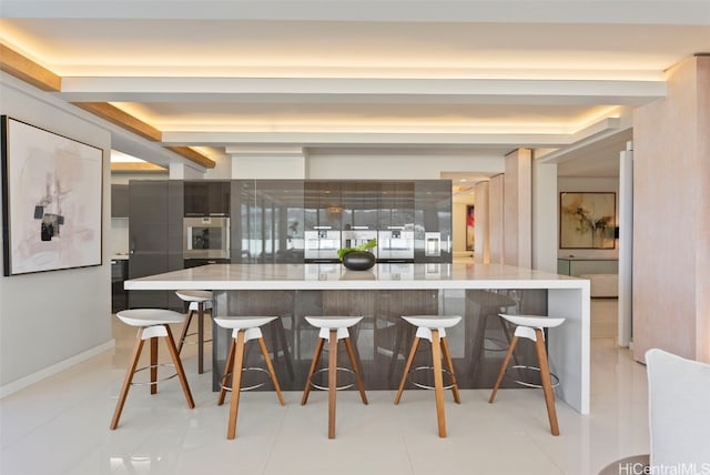 kitchen featuring oven, light tile patterned floors, and a breakfast bar area