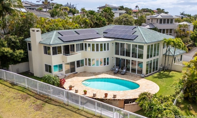 rear view of property with a yard, a patio, solar panels, and a fenced in pool