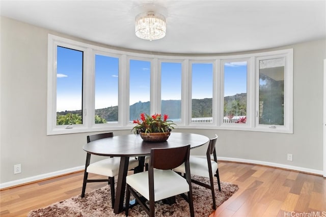 dining area featuring an inviting chandelier, light hardwood / wood-style floors, and a mountain view