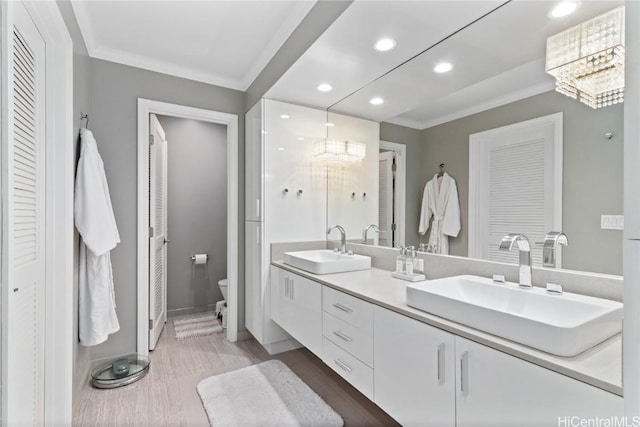 bathroom with toilet, an inviting chandelier, wood-type flooring, crown molding, and vanity