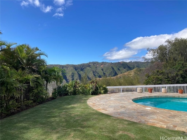 view of swimming pool featuring a patio area, a mountain view, and a yard