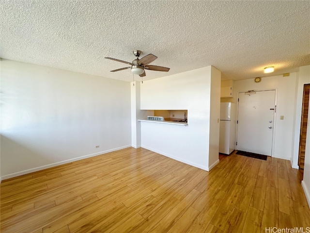 unfurnished living room featuring ceiling fan, a textured ceiling, and light hardwood / wood-style flooring