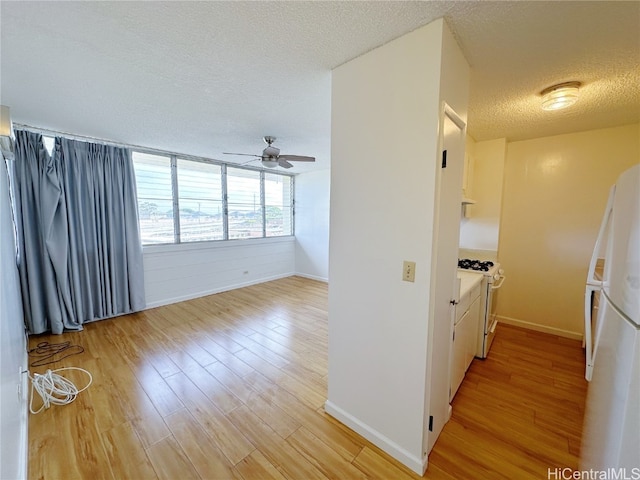 kitchen with light hardwood / wood-style flooring, a textured ceiling, ceiling fan, and white appliances